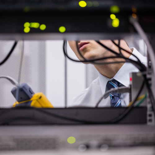 energy storage solutions - technician checking levels in between racks of power storage batteries